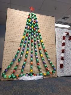 a christmas tree made out of legos is displayed in front of a cardboard wall