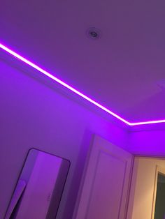 a purple light shines on the ceiling in a room with white walls and cabinets