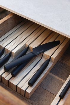 five knives are sitting in a wooden drawer