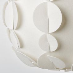 an abstract sculpture made out of white paper with circles and leaves on the bottom half