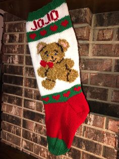 a christmas stocking hanging from a brick wall with a teddy bear on it's sock