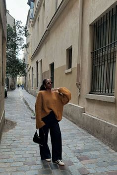 a woman standing in an alley way with her hand on her hip and looking off to the side