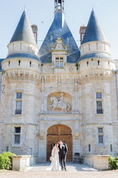 a bride and groom standing in front of an old castle like building with blue turrets