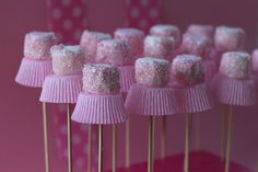 there are many pink cupcakes on the sticks