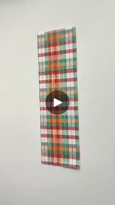 a piece of cloth hanging on the wall with a video play button in front of it