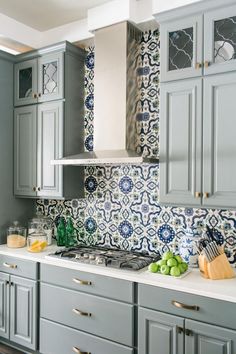 a kitchen with blue and white tiles on the backsplash, cabinets and counter tops