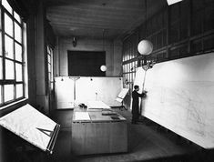 an old black and white photo of a man standing next to a desk in a room