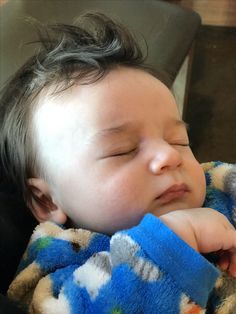 a baby sleeping in a car seat with his eyes closed