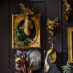 there are some gold deer heads on the wall next to other animal head sculptures and decorations