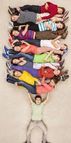 a group of people standing next to each other in front of a wall with their hands up