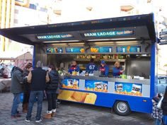 people are standing in line to get food from the ice cream truck that sells them