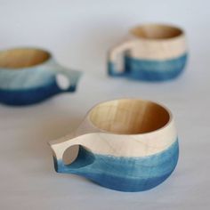 three wooden bowls sitting on top of a white table next to each other, one blue and the other brown