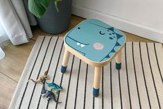 a small child's stool with a dinosaur toy on the floor next to it