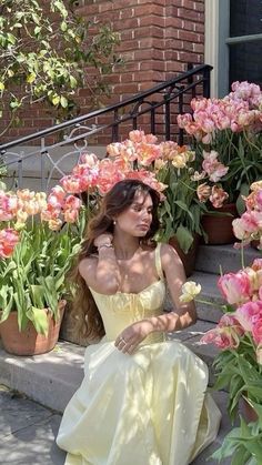 a woman sitting on the steps in front of flowers