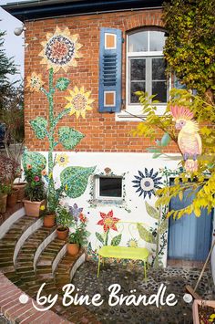 a house painted with sunflowers and other flowers on the outside wall is shown