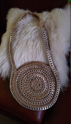 a purse sitting on top of a brown leather chair next to a white fur pillow