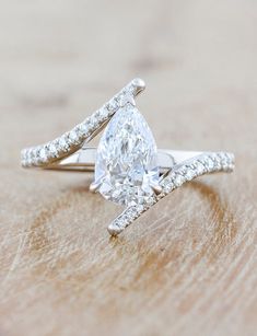 a pear shaped diamond ring on top of a wooden table