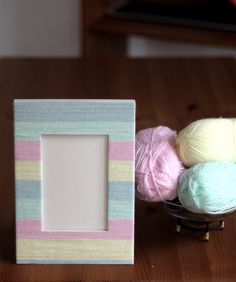 a wooden table topped with balls of yarn next to a frame and ball of yarn