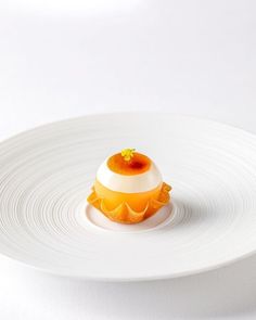 a white plate topped with an orange and cream dessert on top of it's side