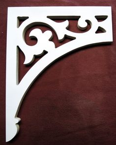 a white metal shelf bracket on a brown surface with an ornate design in the middle