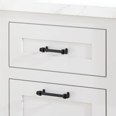 a white cabinet with black handles and knobs