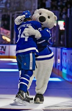 a couple of people that are hugging each other in front of an ice hockey rink