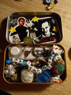 an open tin filled with assorted items on top of a wooden table