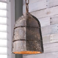 an old rusty light hanging from a chain on a white wooden wall with shutters in the background