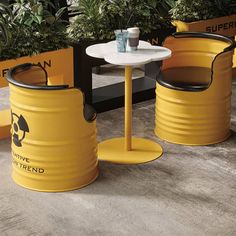 two yellow barrel tables and chairs in front of some potted plants on the ground