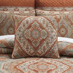 a bed with orange and blue pillows on top of it next to a white pillow