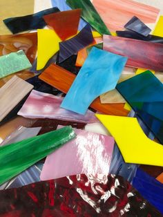 many different colored pieces of glass sitting on top of each other in the middle of a pile