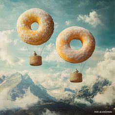 two donuts are being lifted by parachutes in the air over mountains and clouds