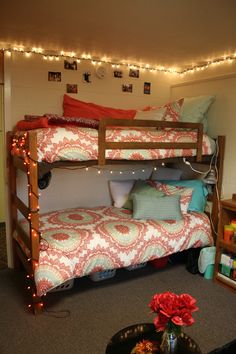 a room with bunk beds and christmas lights on the ceiling, decorated in red and white