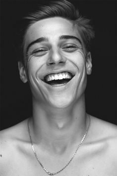 a black and white photo of a young man with his face painted like a smile