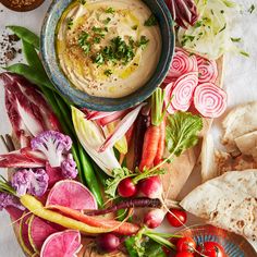 a bowl of hummus, carrots, radishes and other vegetables