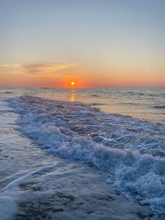 the sun is setting over the water at the beach