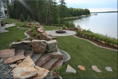 an outdoor fire pit surrounded by rocks and grass