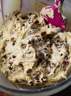 a mixing bowl filled with batter and chocolate chip toppings on top of a wooden table