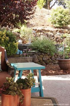 a blue table sitting in the middle of a yard next to some potted plants