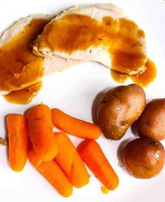 a white plate topped with meat, potatoes and carrots next to gravy