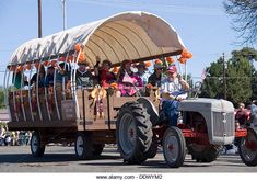 people are riding in the back of an old fashioned tractor during a parade on a sunny day