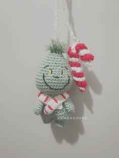 a crocheted christmas ornament with a candy cane hanging from it's side