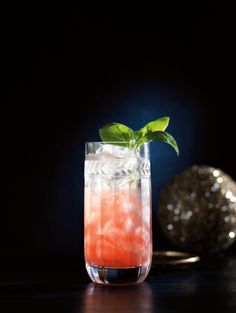 a glass filled with liquid and a green leaf