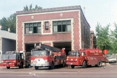 three fire trucks parked in front of a building