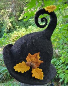 a black hat with an orange and yellow leaf decoration on it's head in the woods