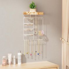 a shelf with jewelry hanging from it and a plant on top of the shelf next to it