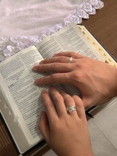 a woman is reading a book with her wedding ring on it's finger and holding an open bible