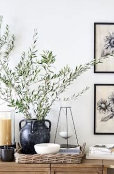 a table topped with vases filled with flowers next to pictures on the wall above it