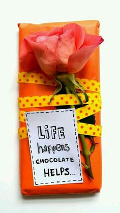 an orange box with a pink rose on it and a sign that says life happens chocolate helps