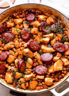 a pan filled with sausage and beans on top of a table